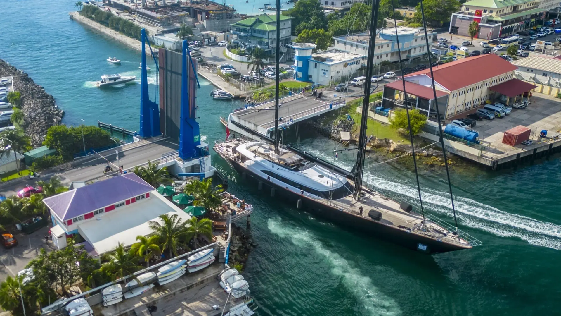 Aerial view of the SMYC Bar & Restaurant and its deck as a large sailing yacht passes through the open Simpson Bay bridge
