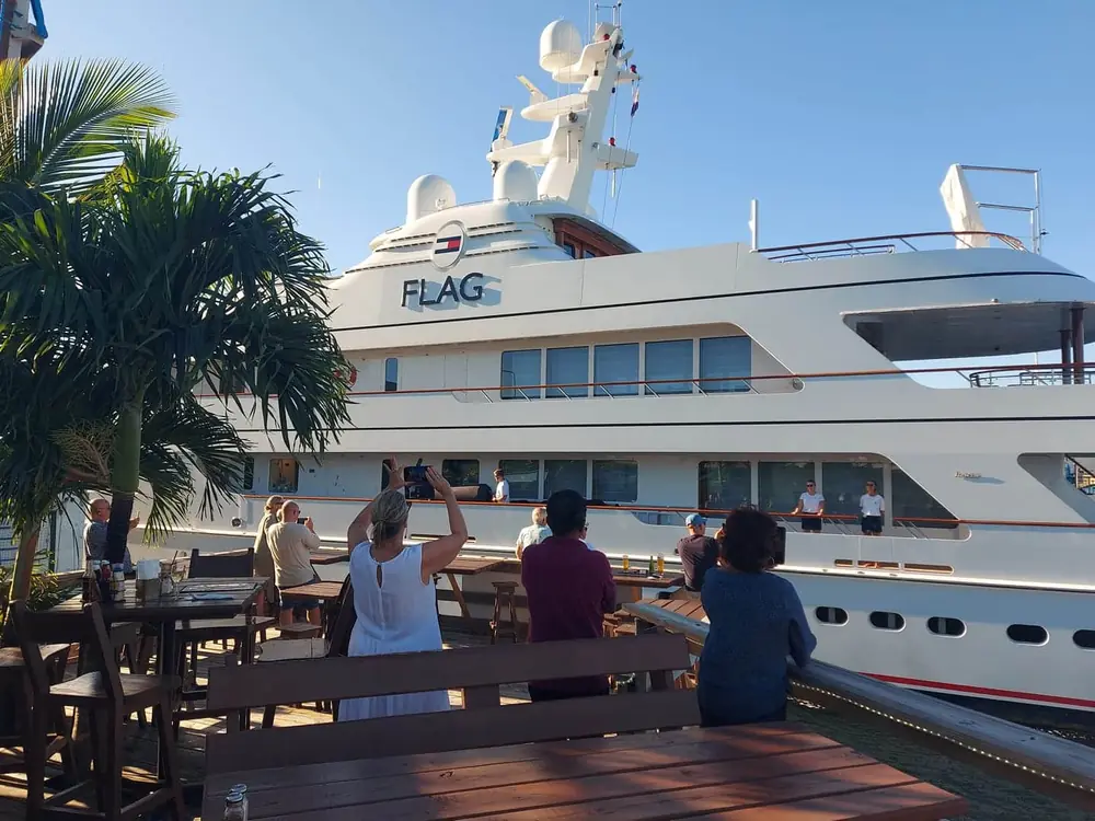 Guests on the lower deck watching a superyacht pass through the bridge channel