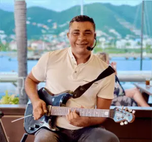A guitarist playing with the lagoon and hills behind him